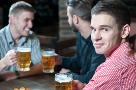 Meeting at the pub. Three happy friends drinking beer at the pub
