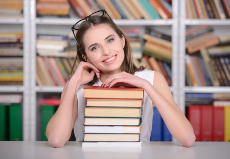 Portrait of a beautiful young student girl reading book in library
