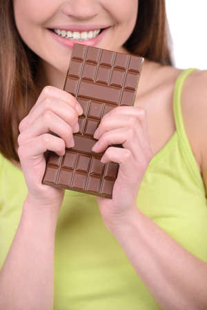 Portrait of a young woman eating a chocolate bar against a white backgroundの写真素材