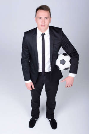 Full length portrait of a young handsome businessman kicking a football isolated on white backgroundの写真素材