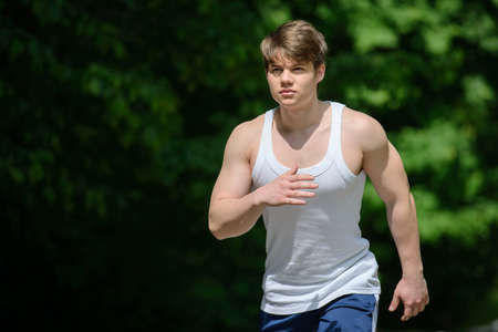 Running sport man. Fit muscular young male runner sprinting at great speed outdoors on road.の写真素材