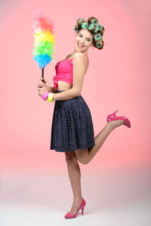 The house is shining. Happy young housewife standing on one leg with a brush in her handの写真素材