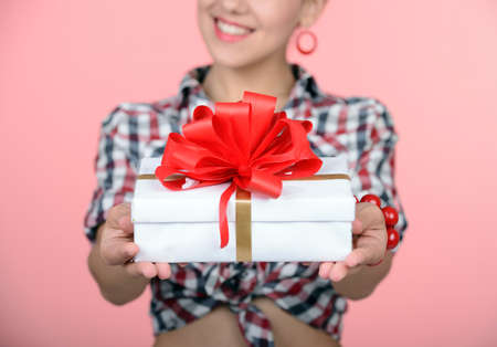 I love surprises! Happy young pin-up girl holding a present box in her left hand and standing on one legの写真素材