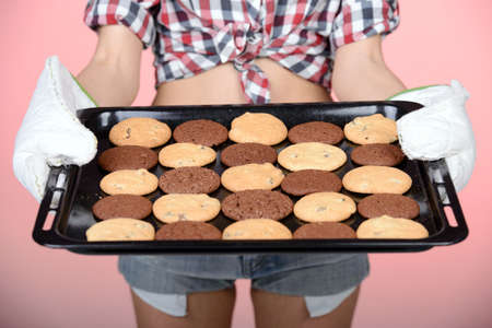 I've cooked this for you! Happy young housewife standing with a pan full of cakesの写真素材