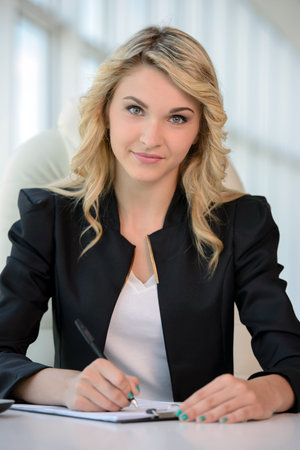 Business woman at the office. Young beautiful business woman at work in his officeの写真素材