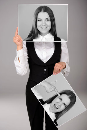 A young business woman holds two portraits of different emotions to choose from today. Gray...