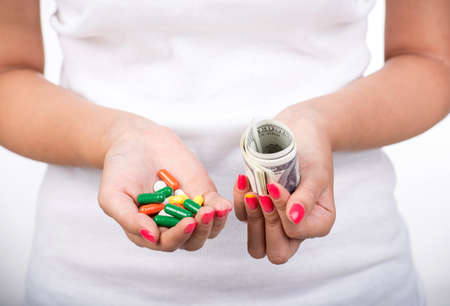 Close-up woman in white is taking the pills and money. Expensive drugs.の写真素材