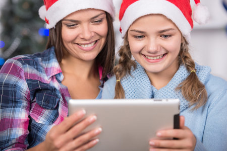 Beautiful young woman and her daughter with the tablet at Christmas time. Close-up.の写真素材