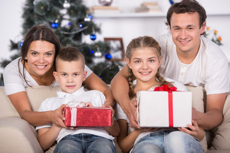 Portrait of friendly family with gifts are looking at camera on Christmas evening.の写真素材