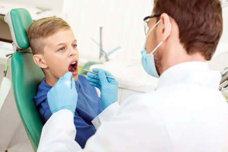 The doctor treats a tooth of little boy at dentist's clinic.