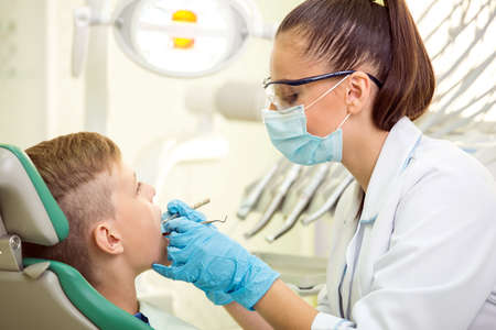 The female doctor treats a tooth of little boy at dentist's clinic.の写真素材