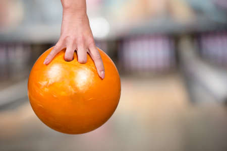 Close-up hand of woman is holding ball against bowling alley.の写真素材