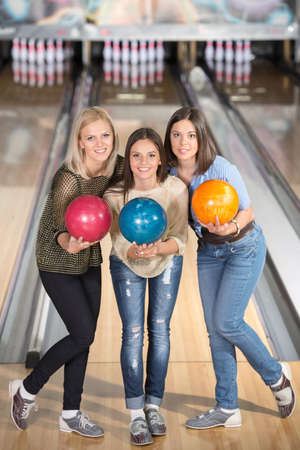 Smiling group of female friends bowling and are holding balls.の写真素材