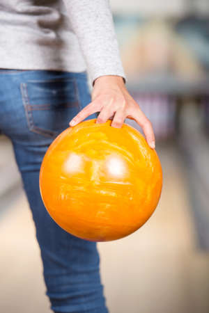 Close-up hand of young woman is holding ball against bowling alley.の写真素材