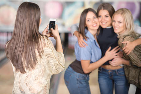 Group of female friends are taking picture with mobile phone.の写真素材