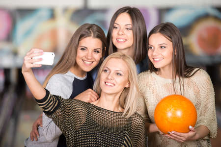 A group of young female friends are taking a self portrait with a phone in bowling club.の写真素材