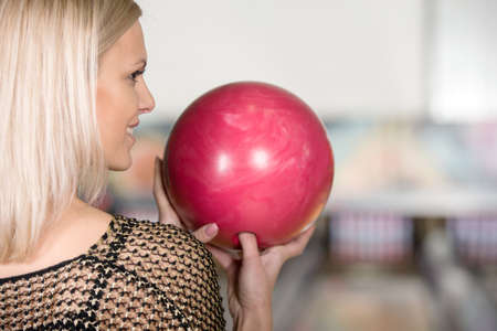 Portrait of beautiful young woman with a bowling ball in her hands, back view.の写真素材