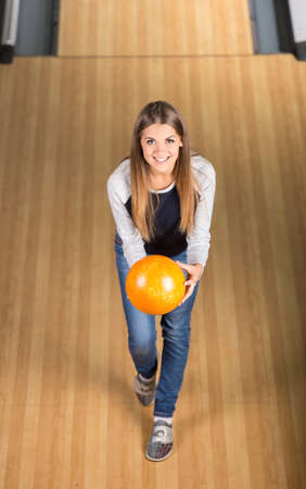 Smiling young woman in a bowling alley is having fun, view from above.の写真素材