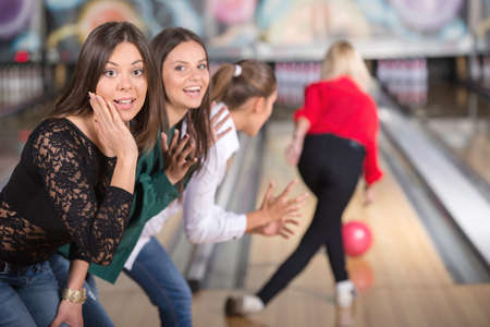 Girls in bowling looking into the camera, when their friend is throwing the ball.の写真素材