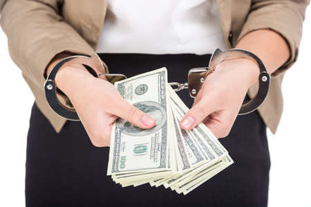 Close-up of woman is holding in hand a lot american dollars, isolated on white . A handcuffs on her hands.の写真素材