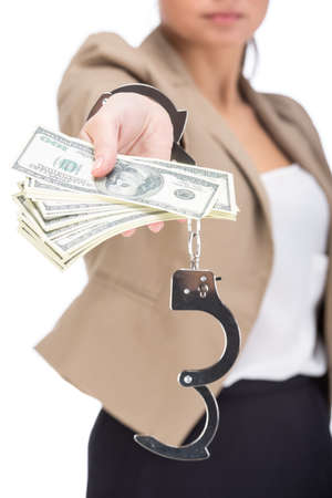 Young woman is holding in hand a lot american dollars, isolated on white . A handcuffs on her hands.の写真素材