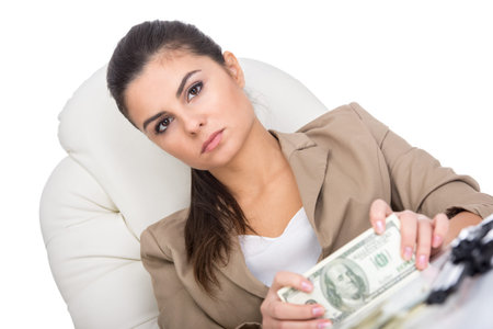 A young business woman at the table with a lot of money and gun, isolated on white background.の写真素材