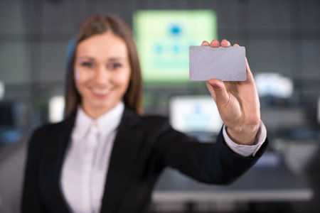 Portrait of a handsome young woman with discount card is standing in the background of the modern conference hall.の写真素材