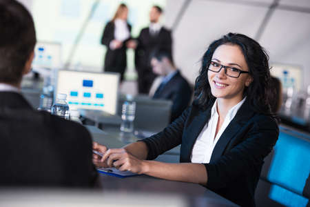 Young smiling business woman is looking at the camera during presentation in modern conference hall.の写真素材