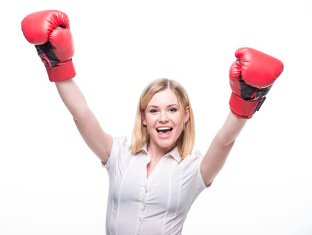 Business woman is wearing boxing gloves and business suit on the white background.
