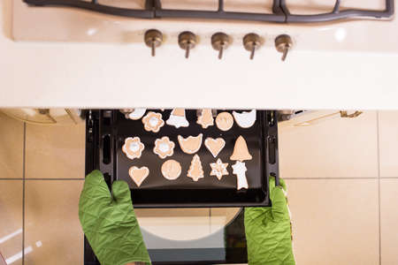 Top view hands of somebody who pulls cookies from the oven.の写真素材