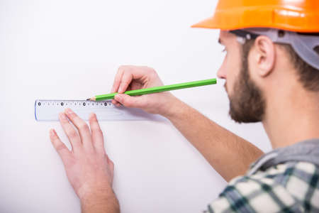 Builder in helmet with a tape measure on a white background.の写真素材