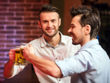 Two handsome friends in a pub with glasses of beer.の写真素材