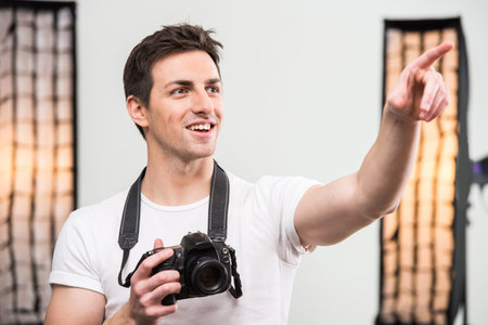 Young smiling photographer with camera in professionally equipped studio. Close-up.の写真素材