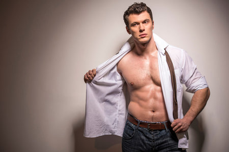 Portrait of  muscular man removing his shirt isolated over white background.の写真素材