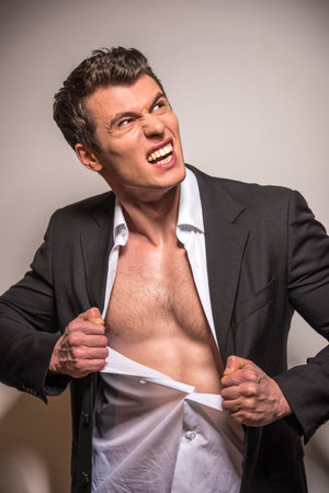Portrait of muscular man is ripping his shirt isolated over white background.の写真素材