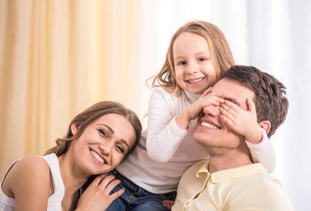 Mother, father and daughter. Portrait of happy family sitting on sofa.の写真素材