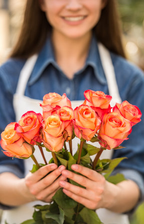Close-up. Female florist holding bouquet with roses. Focus on roses.の写真素材