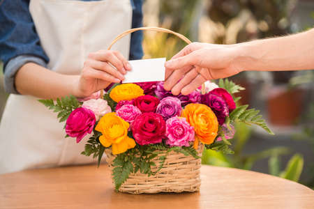Close-up. Detail view of seller florist giving visit card to the customer.の写真素材