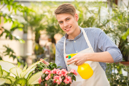 Young handsome male florist spraying flowers in shop.の写真素材