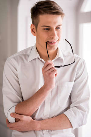 Portrait of smiling young handsome male with glasses in white shirt.の写真素材