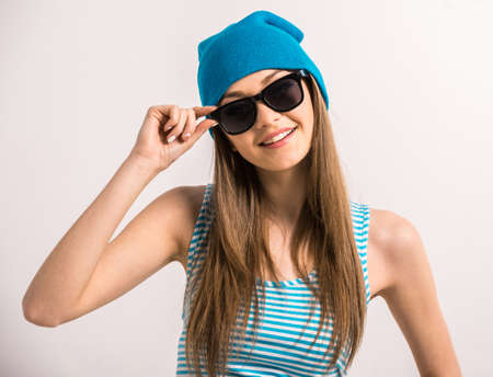 Beautiful young woman  is posing in casual clothes and sunglasses over grey background.の写真素材