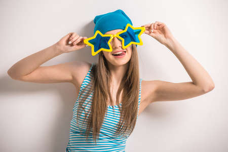 Cheerful young girl is posing on gray background in glasses in the shape of stars.の写真素材
