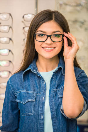 Portrait of happy young woman buying a new glasses at optician store.の写真素材