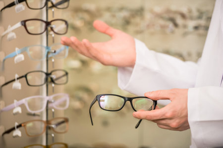 Young man (only hands) at optician with glasses is showing a glasses.の写真素材