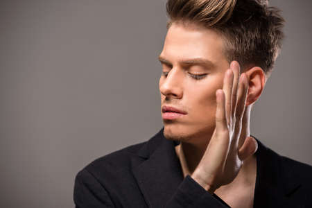 Young handsome man in tuxedo posing in the studio on dark background. Fashion portrait.の写真素材
