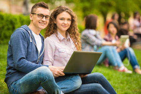 Couple of attractive smiling students dressed casual having fun outdoors on campus at the university.の写真素材