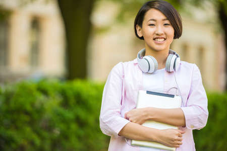 Young beautiful smiling asian student  outdoors on campus at the university.の写真素材