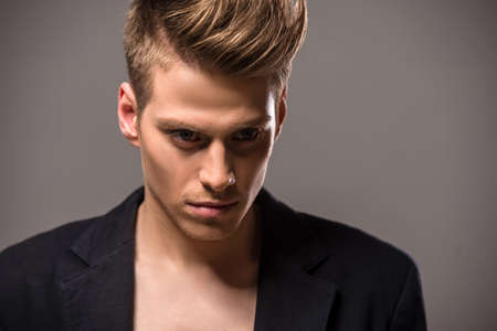 Young handsome man in tuxedo posing in the studio on dark background. Fashion portrait.の写真素材