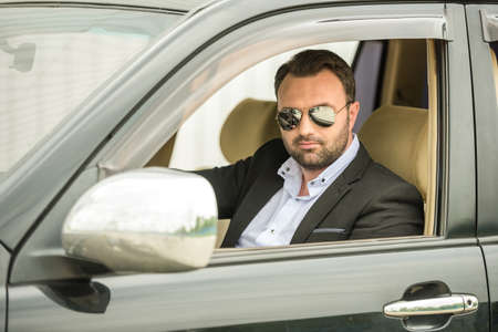 Successful mature man in formal wear sitting in classy car.の写真素材