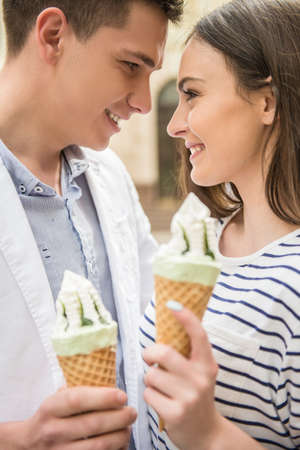 Young beautiful couple walking in the street and enjoying ice-cream. Romantic date.の写真素材